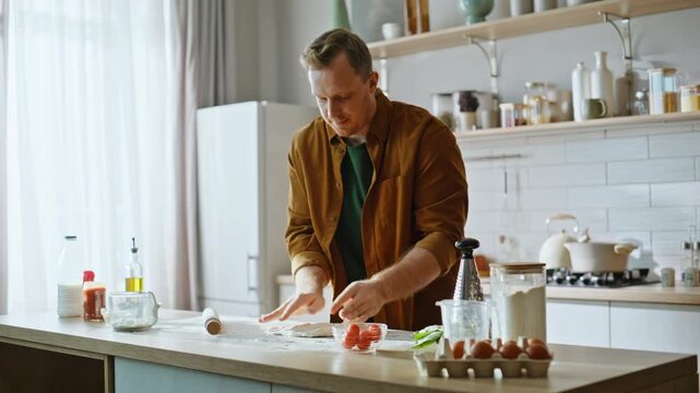 Focused man rolling dough kitchen counter involved in culinary process closeup.