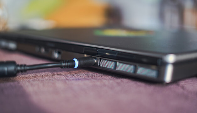 Close-up of a laptop charging cable plugged into a power port