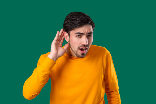 Young Man Pointing To Ear With Confused Face, Signaling He Cant Hear Clearly