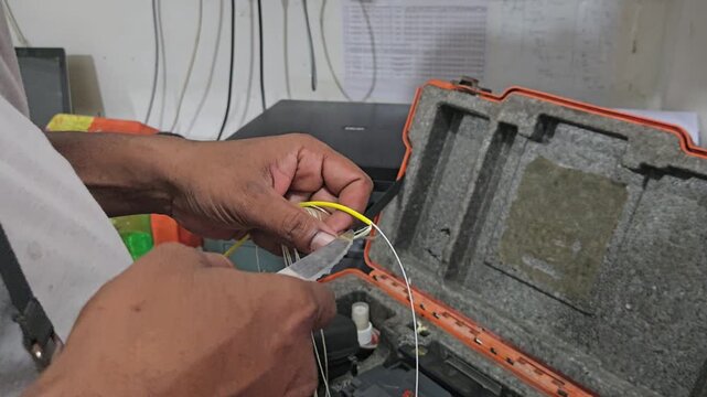 Close-up of a technician performing fiber optic fusion splicing using a precision machine to connect optical cables. The footage highlights high-speed internet infrastructure