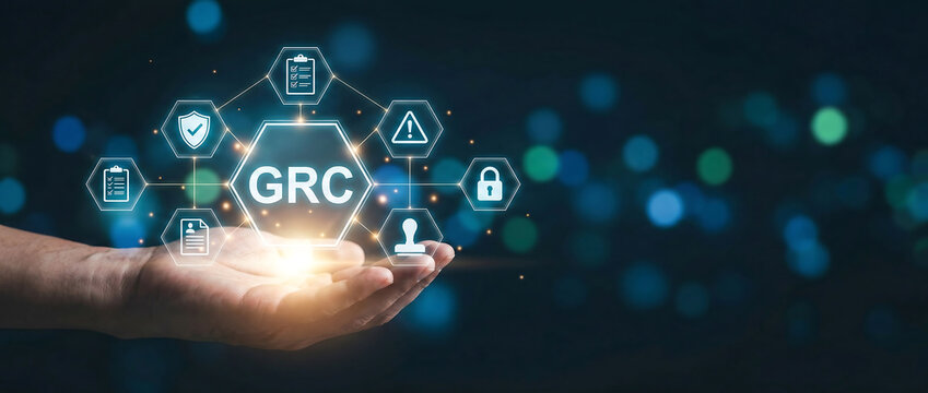 Hand holding glowing GRC governance risk compliance hologram icons with futuristic digital background and cybersecurity elements