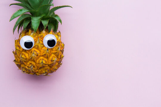Pineapple with eyes on pink background
