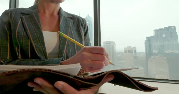 Businesswoman Writing Notes in High-Rise Office