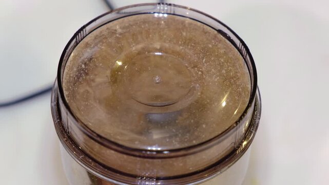 Top view of a coffee grinder milling flax seeds into fine powder, lid fogged with motion on a clean counter at home. Fresh ground flax adds fiber and omega3 to support healthy breakfasts.