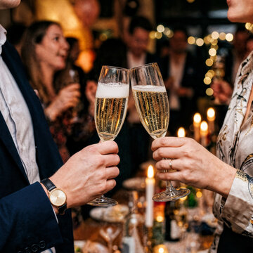 Two hands with glasses of champagne cheering, celebrating new year's eve, toast, cheering, wedding and birthday, special event, celebrating together, party, anniversary, sparkling wine