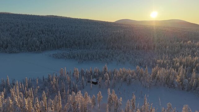 Golden sunlight floods the serene landscape of Akaslompolo, revealing white-covered trees and peaceful snow. The tranquil beauty of Lapland captivates as day breaks over the horizon.