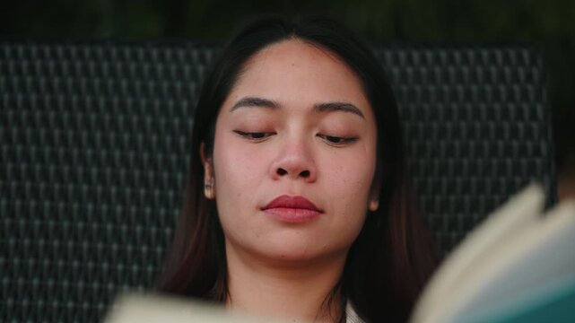 Focused woman reading book outdoors on a chaise lounge