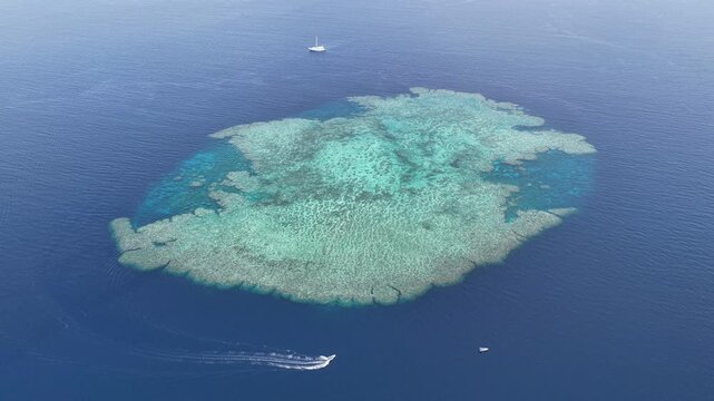 Seen from a bird's eye view, an impressive platform reef, named "E6," sits in the midst of the Bligh Channel east of Viti Levu, Fiji. The reef is home to extensive coral growth and fish diversity.