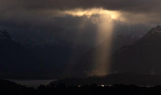 Single sun ray over Lake Nahuel Huapi after rain with first snow on Andes, view from Cerro Bayo, Patagonia, Argentina