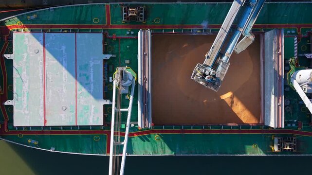 Top-down aerial video showing a bulk carrier ship being loaded with grain at the Seaforth terminal, featuring the loading arm, open holds, and geometric ship deck details.
