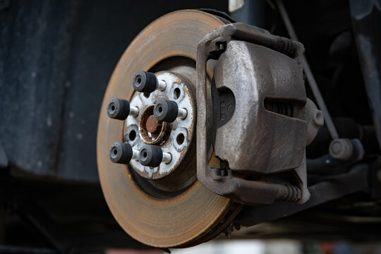 Disc brake of the vehicle for repair, in process of new tire replacement. Car brake repairing in garage.Suspension of car for maintenance brakes and shock absorber systems.Close up.