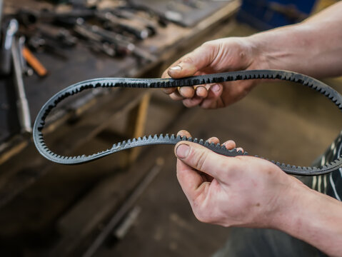 Old worn rubber alternator belt in men's hands. The concept of car maintenance. Copy space.