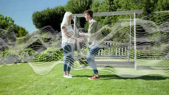 Man kneeling, opening small box, proposing marriage, placing ring on partner, then embracing