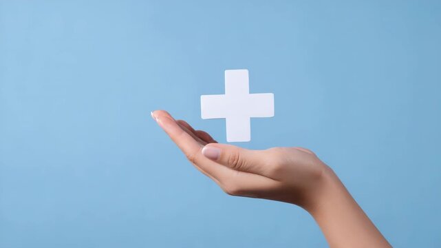 Female hand holding white cross sign on blue background symbolizing health and medicine