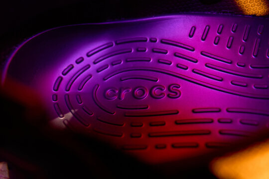 Tyumen, Russia-February 15, 2026: Crocs shoe under blue light, showcasing the brand logo and design features