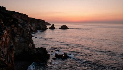 Obraz premium A rocky coastline basks in the warm glow of sunset, with gentle waves lapping at the shore, creating a serene and peaceful seascape.