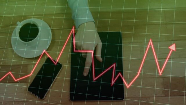 Tapping hand in light longsleeve-shirt using tablet on wood table red chart moving past phone cup