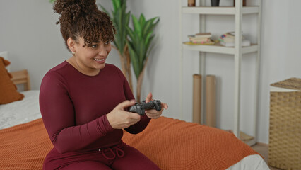 Woman holding game controller, fingers on joystick, smiling and leaning forward, wearing maroon...