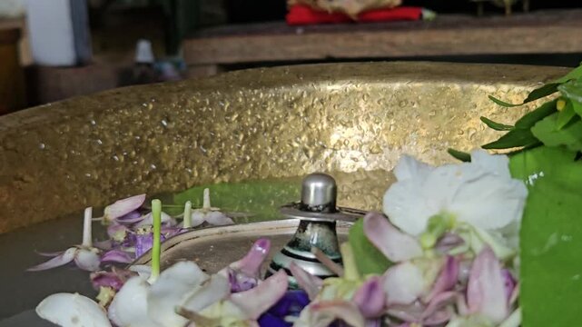 Shivling jal abhishek with flowers and bel leaves in Hindu temple, sacred water offering ritual to Lord Shiva, spiritual scene with devotion, tradition and religious culture in India