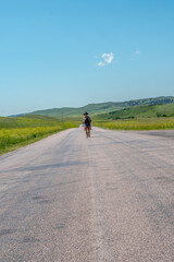 Obraz premium Single traveler walks down quiet rural road under clear blue sky