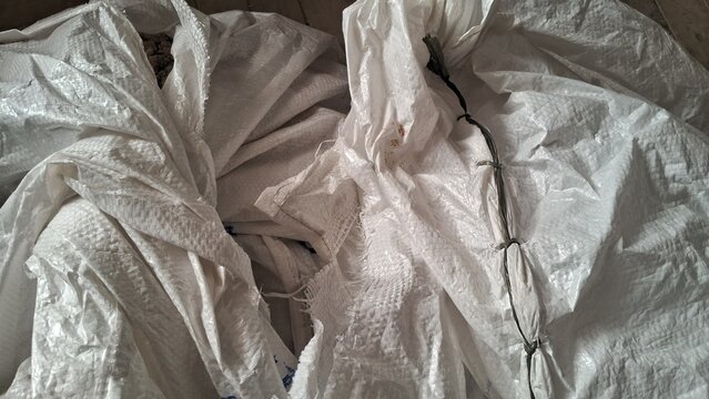 A close-up view of crumpled white woven polypropylene sacks, showing their texture and utilitarian purpose.