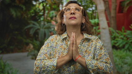 Woman stands in green park showing bare face and eyeglasses amid lush foliage at midday  serenity peace calm. © Krakenimages.com
