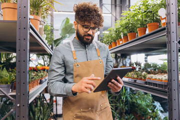 Florist small business owner using digital tablet checking plant inventory in a modern flower shop