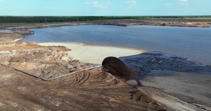 Pipe releasing muddy water and gravel at phosphate mining site during mineral washing and separation process.