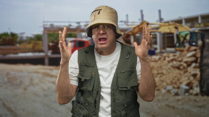 Naklejka premium Man with fishing vest and bucket hat raises hands and shouts with open palms at building; frustration concern.