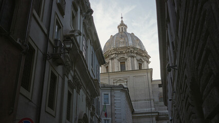 Stone church dome above narrow cobbled street with lantern and italian flag hanging from facade  historic calm. © Krakenimages.com