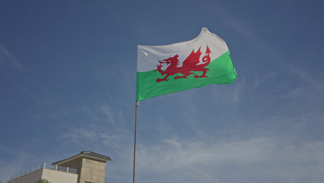 Flag with red dragon motif waving on flagpole above building rooftop under clear blue sky, wind driven motion captured in a six frame sequence; national pride.