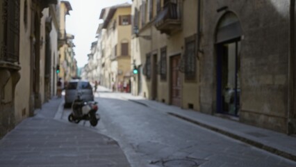 Naklejka premium Narrow historic street defocused with soft bokeh, scooter and building facades blurred street; background backplate copyspace calm.