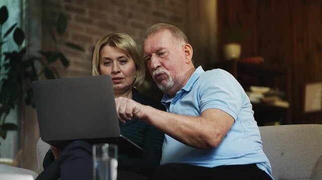 Senior man and adult daughter choosing home furniture on laptop, shopping online
