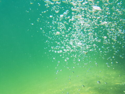 Air bubbles underwater in clear turquoise water abstract aquatic background

