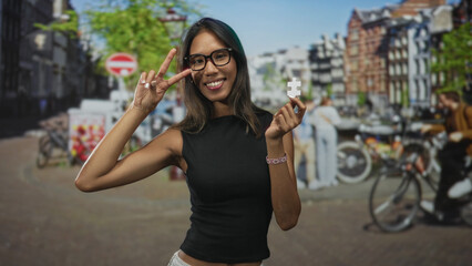 Naklejka premium Thai woman holds white puzzle piece and flashes peace sign with right hand on a street lined with bicycles and brick buildings; curiosity discovery.