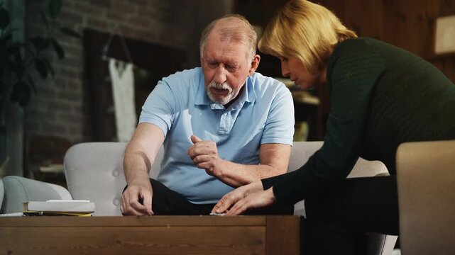 Thoughtful senior man and his daughter connecting jigsaw puzzle pieces, pastime