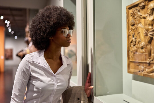Woman wearing glasses and looking at exhibition. Concept of Museum Day.