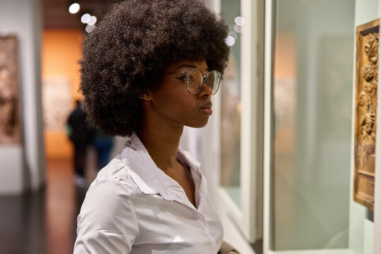 Woman wearing glasses and looking at exhibition. Concept of Museum Day.