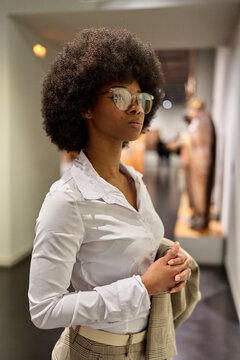Woman wearing glasses and looking at exhibition. Concept of Museum Day.