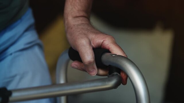 Weak senior male with disability standing up using a walker, rehabilitation