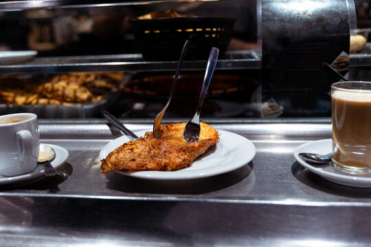 Close-up of a freshly prepared torrija being served in a traditional Spanish bar. Typical Spanish gastronomy scene with warm atmosphere and focus on dessert texture.