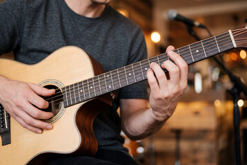 Obraz premium Close up of a man skillful hands playing a wooden acoustic guitar in a music studio setting
