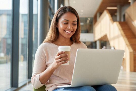 Happy university student using laptop during coffee break
