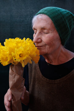 Elderly woman holds and smells yellow flowers