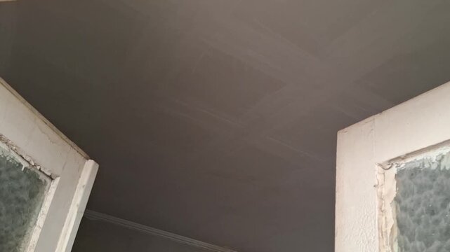 Weathered old wooden door frames slowly moving to reveal a dark gray ceiling renovation video.