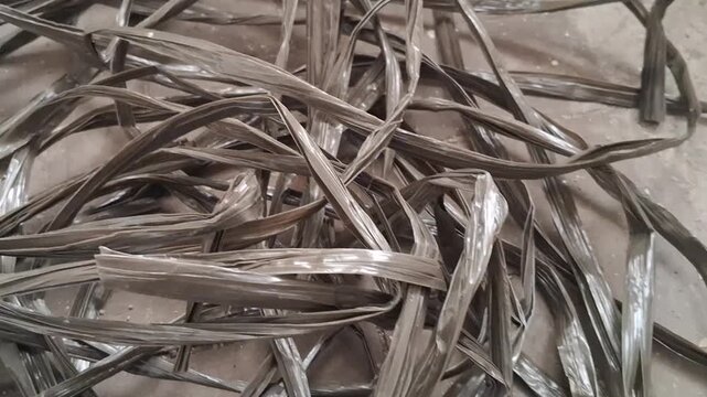 Close-up motion of dark, crumpled plastic strips forming an abstract, tangled texture video background.