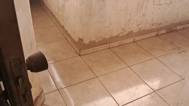 Hand opening old metal security gate revealing tiled hallway floor motion footage