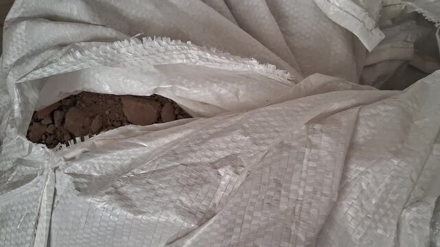Heavy duty woven polypropylene sack material partially open revealing dry earth material footage