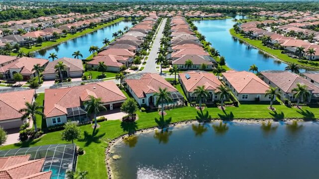 Aerial view of a suburban neighborhood with rows of houses, lakes, and palm trees, showcasing a luxury lifestyle.