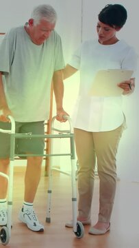 Vertical video: Rehab therapist cueing senior with walker while checking clipboard, noting gains